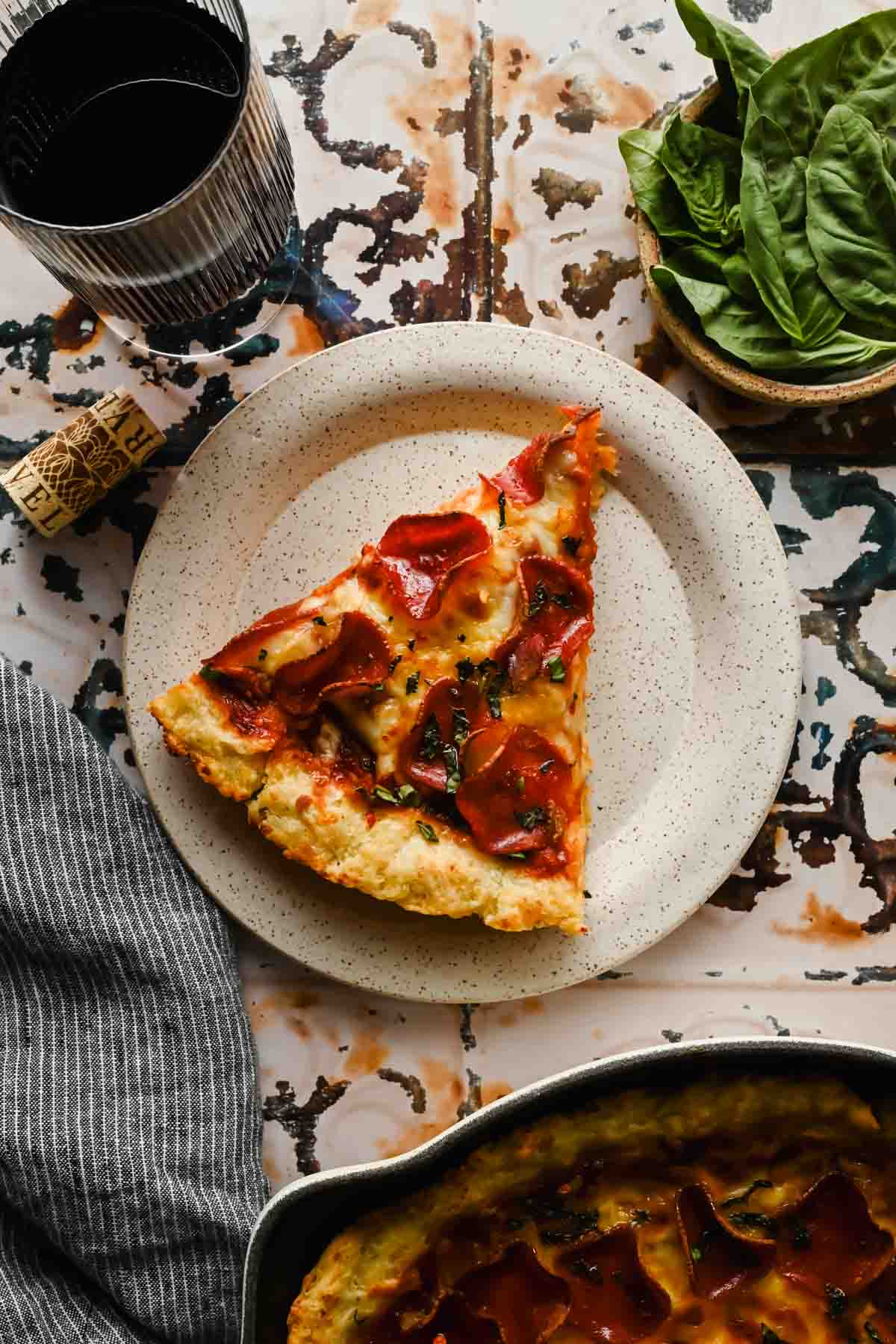 slice of spatula skillet pizza topped with pepperoni, melty cheese and fresh herbs on white serving plate.