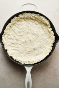 pizza dough pushed into cast iron skillet.