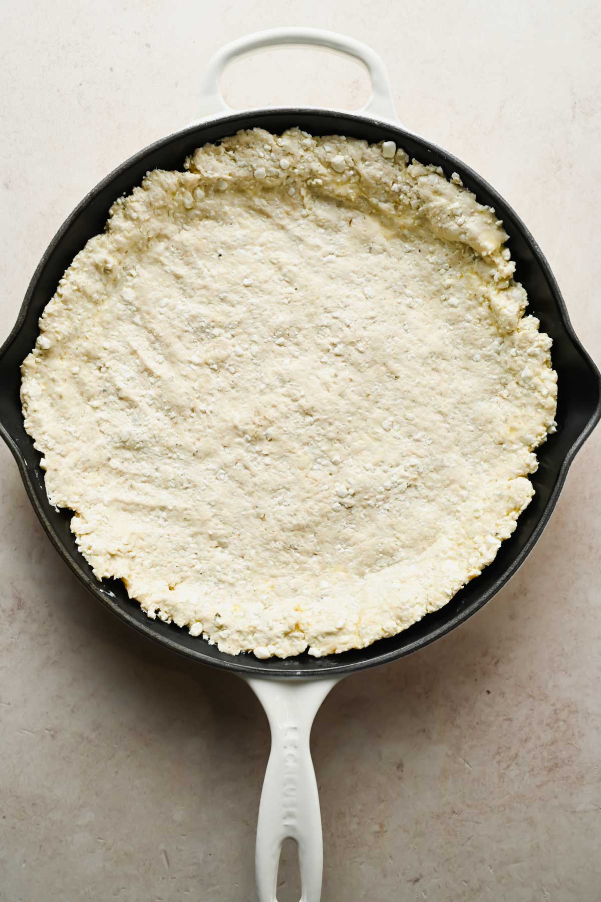 pizza dough pushed into cast iron skillet.