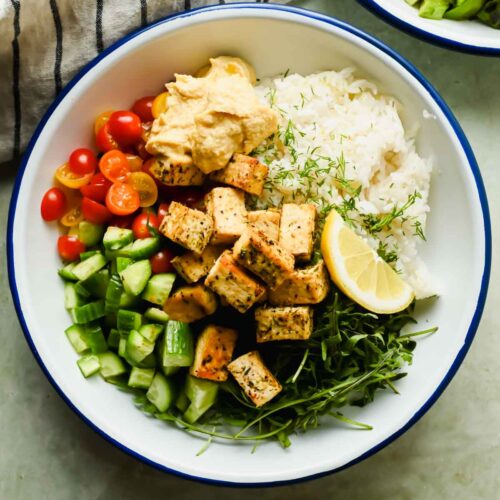 Mediterranean tofu bowl with herbed rice, cucumber, tomato and crispy tofu pieces.