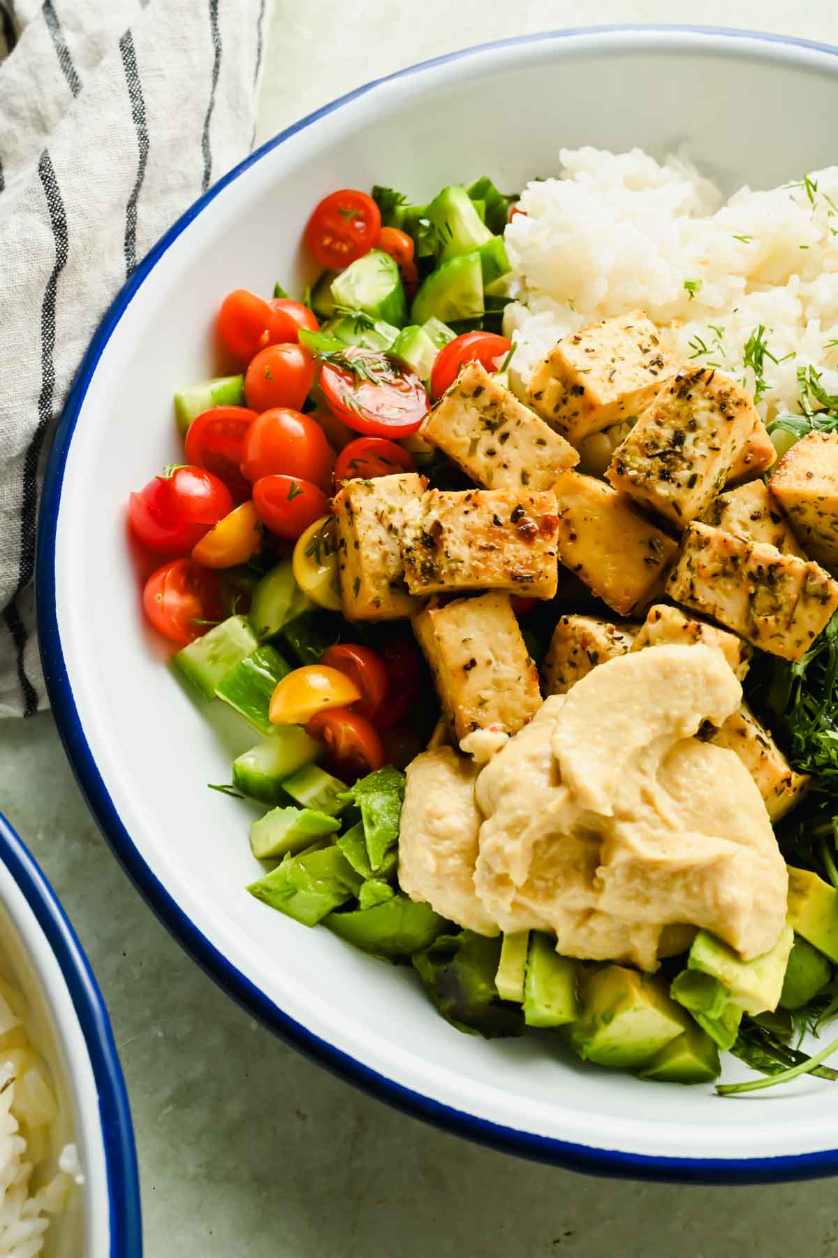 Mediterranean tofu bowl with herbed rice, cucumber, tomato and a dollop of hummus.