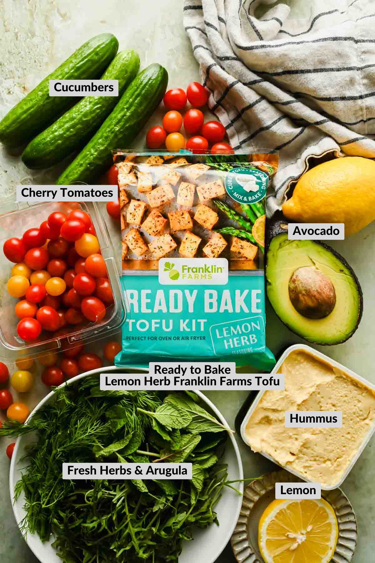 labeled ingredients for mediterranean tofu bowl arranged on stone background.