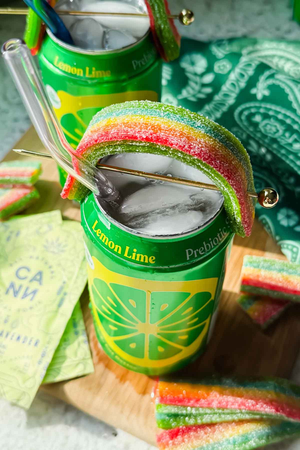 open canned cocktail garnished with airhead extreme shaped like a rainbow on a wood cutting board.