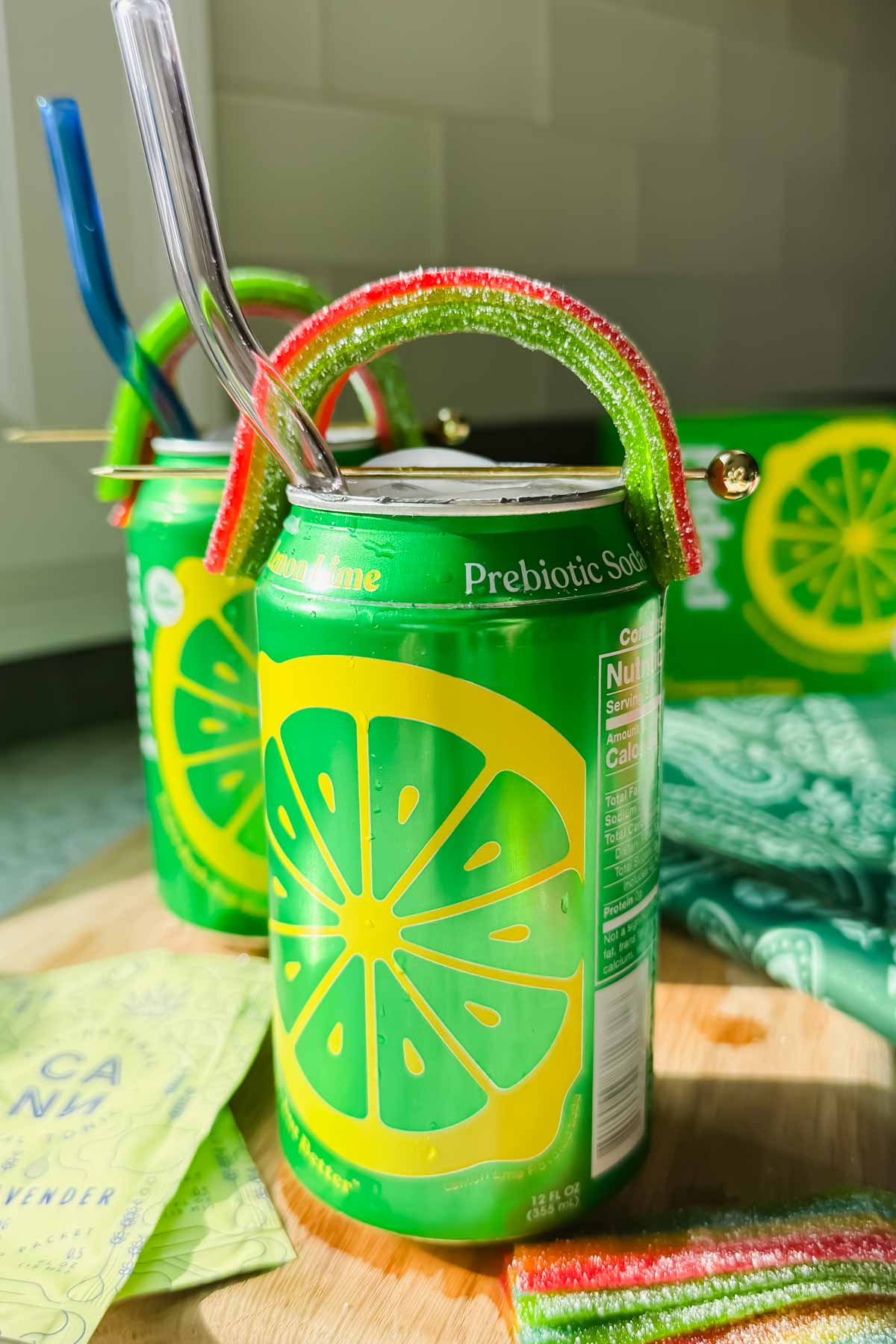 open canned cocktail garnished with airhead extreme shaped like a rainbow on a wood cutting board.