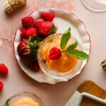 scoop of frozen sangria in a small glass serving dish garnished with mint and plated with strawberries and raspberries.