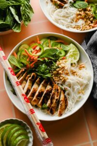Vietnamese Vermicelli Bowl with lemongrass chicken, fresh veggies and herbs plated with chopsticks.