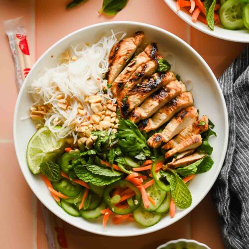 Vietnamese Vermicelli Bowl with lemongrass chicken, fresh veggies and herbs plated with chopsticks.