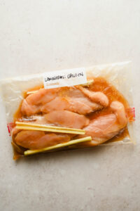 raw chicken breasts in large plastic bag with lemongrass marinade.