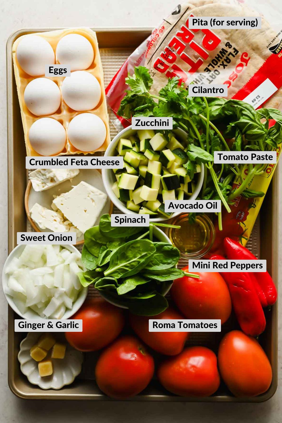 labeled ingredients for shakshuka in individual bowls on a cookie sheet.