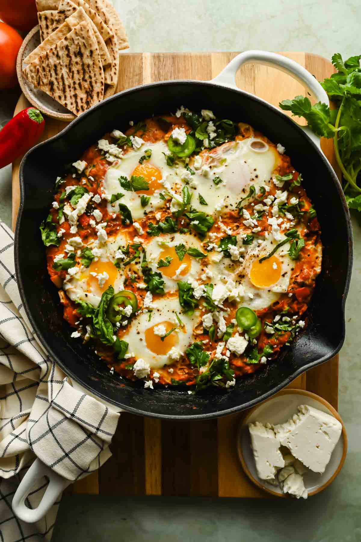 vegetarian shakshuka topped with chopped fresh herbs and feta in cast iron skillet.