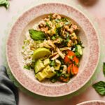 lamb stir fry in speckled bowl served over rice, garnished with avocado, green onion, herbs and veggies.