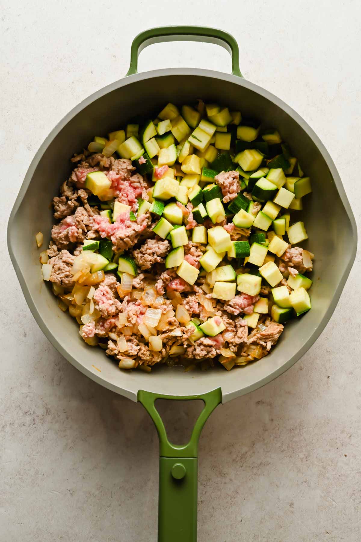ground lamb cooking in large skillet with diced veggies.