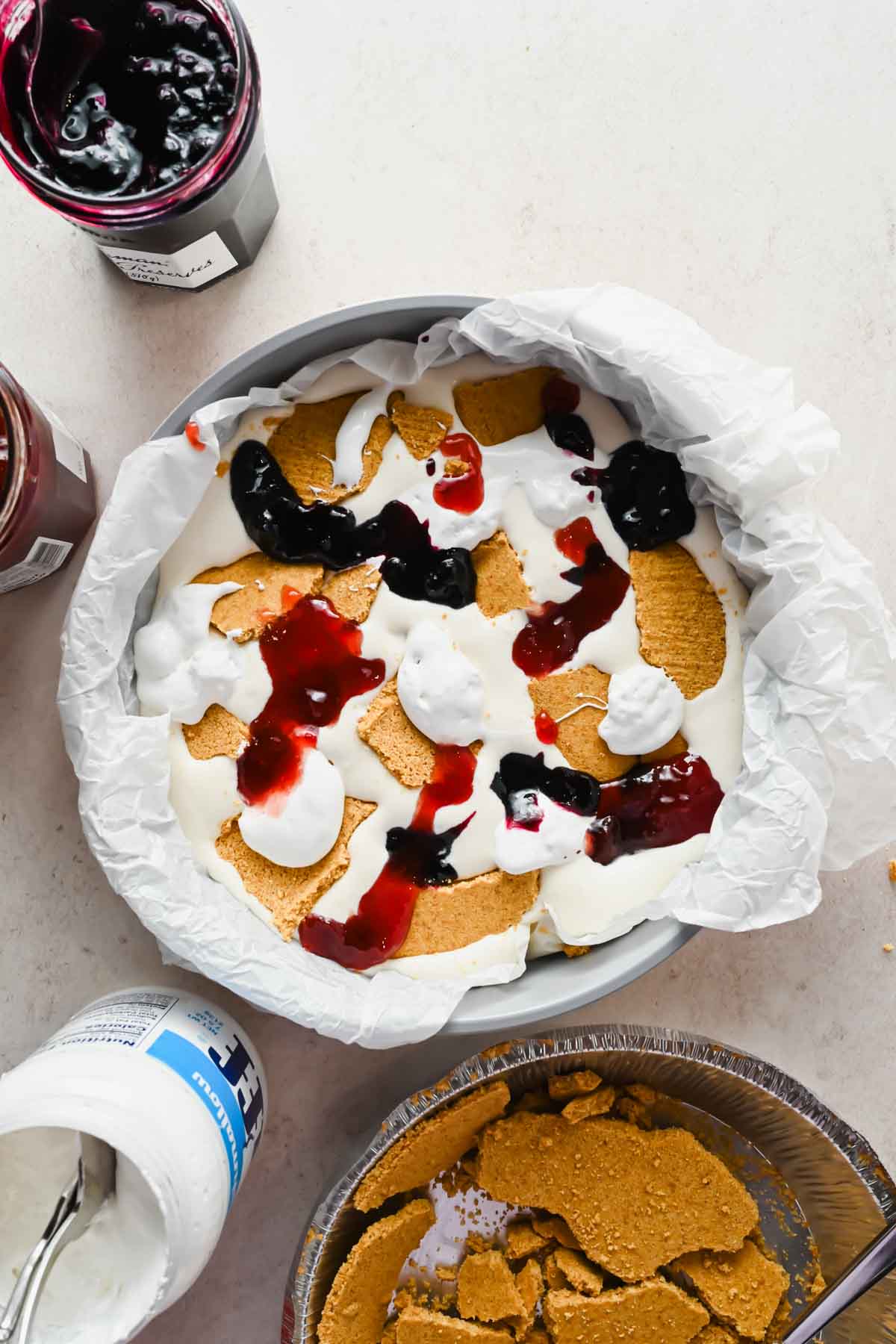 berry jam and graham cracker pieces mixed into whipping cream in pie pan.