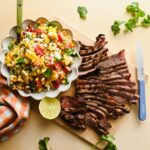 thinly sliced grilled steak beside white bowl of corn salsa.