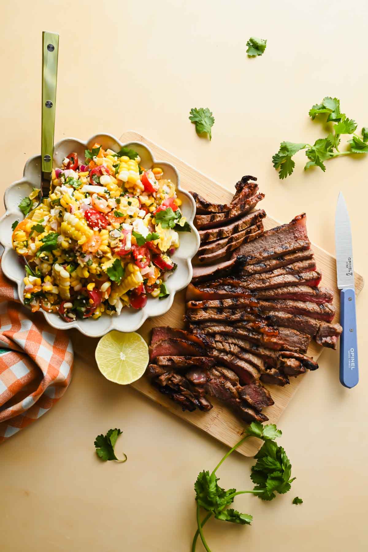 thinly sliced grilled steak beside white bowl of corn salsa.