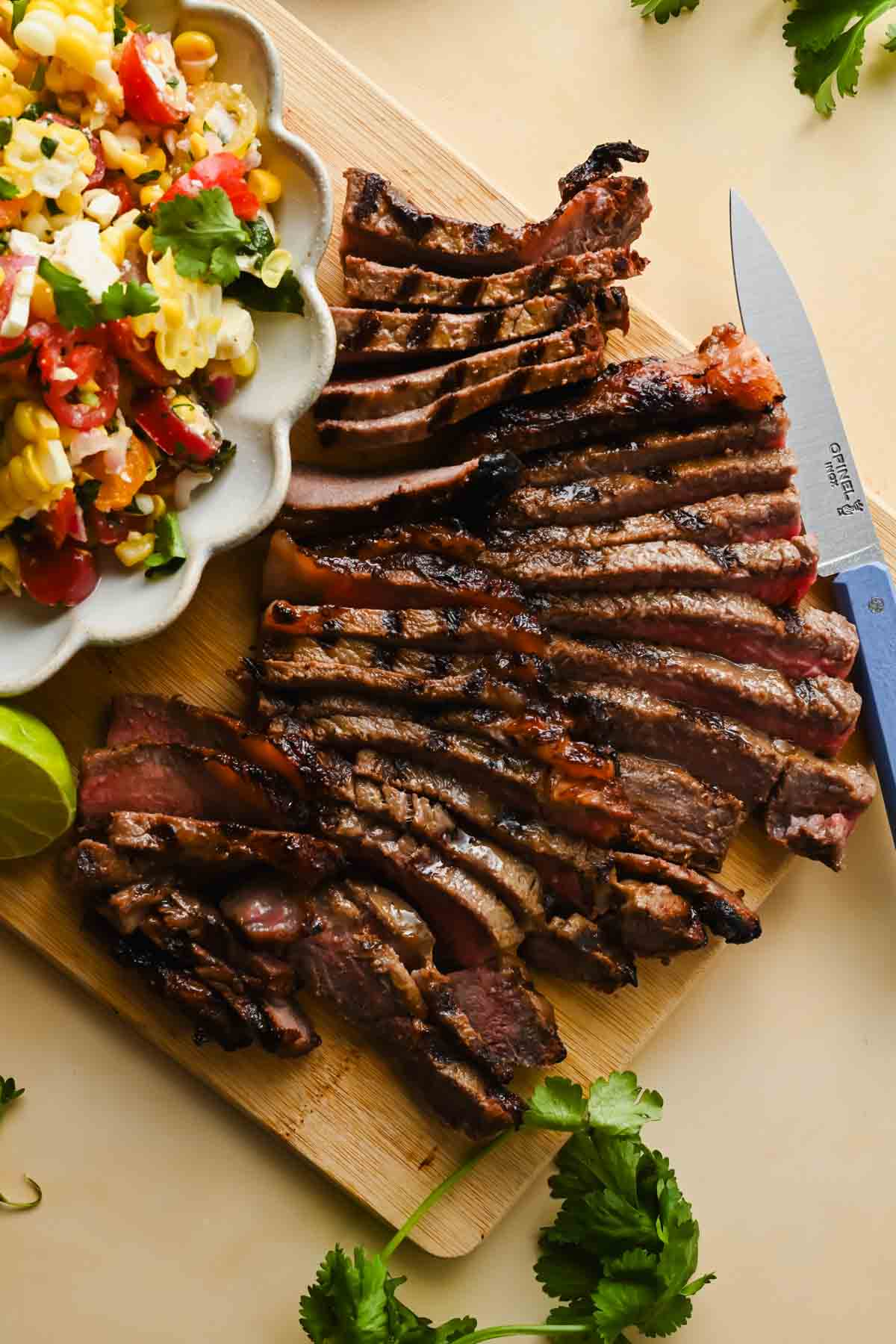 thinly sliced grilled steak beside white bowl of corn salsa.