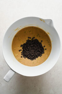 protein zucchini muffin batter in large mixing bowl with chocolate chips added on top.