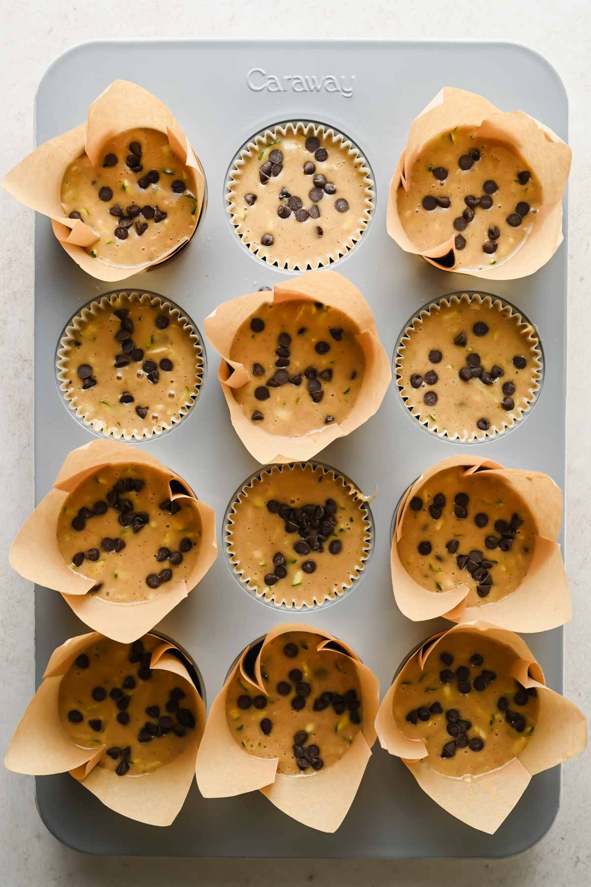 protein zucchini muffin batter in liners in gray muffin tin before baking.