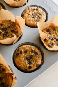 baked protein zucchini muffins in liners in gray muffin tin.