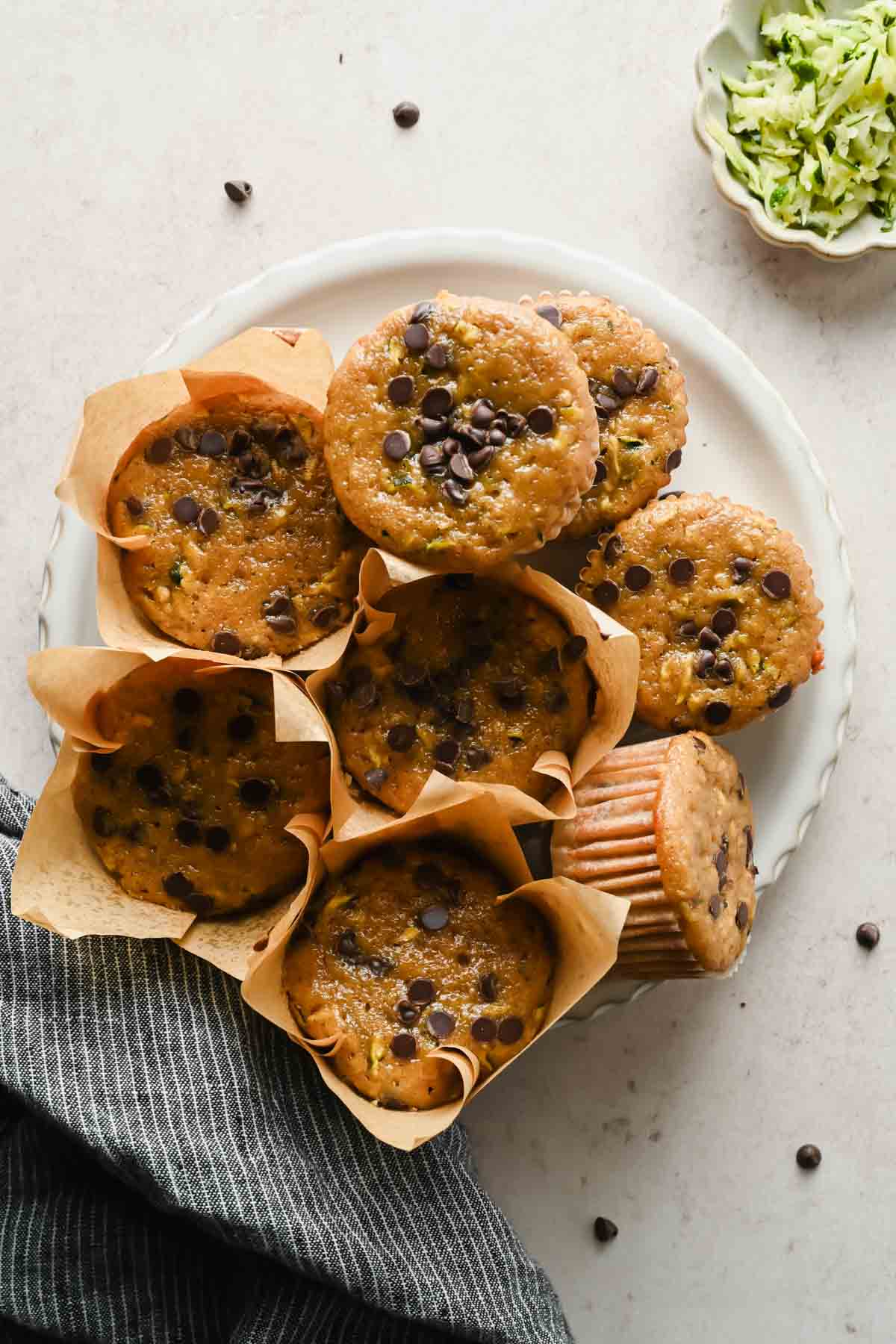 protein zucchini muffins in liners on white plate.