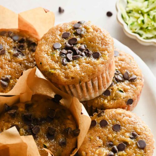 protein zucchini muffins in liners on white plate.