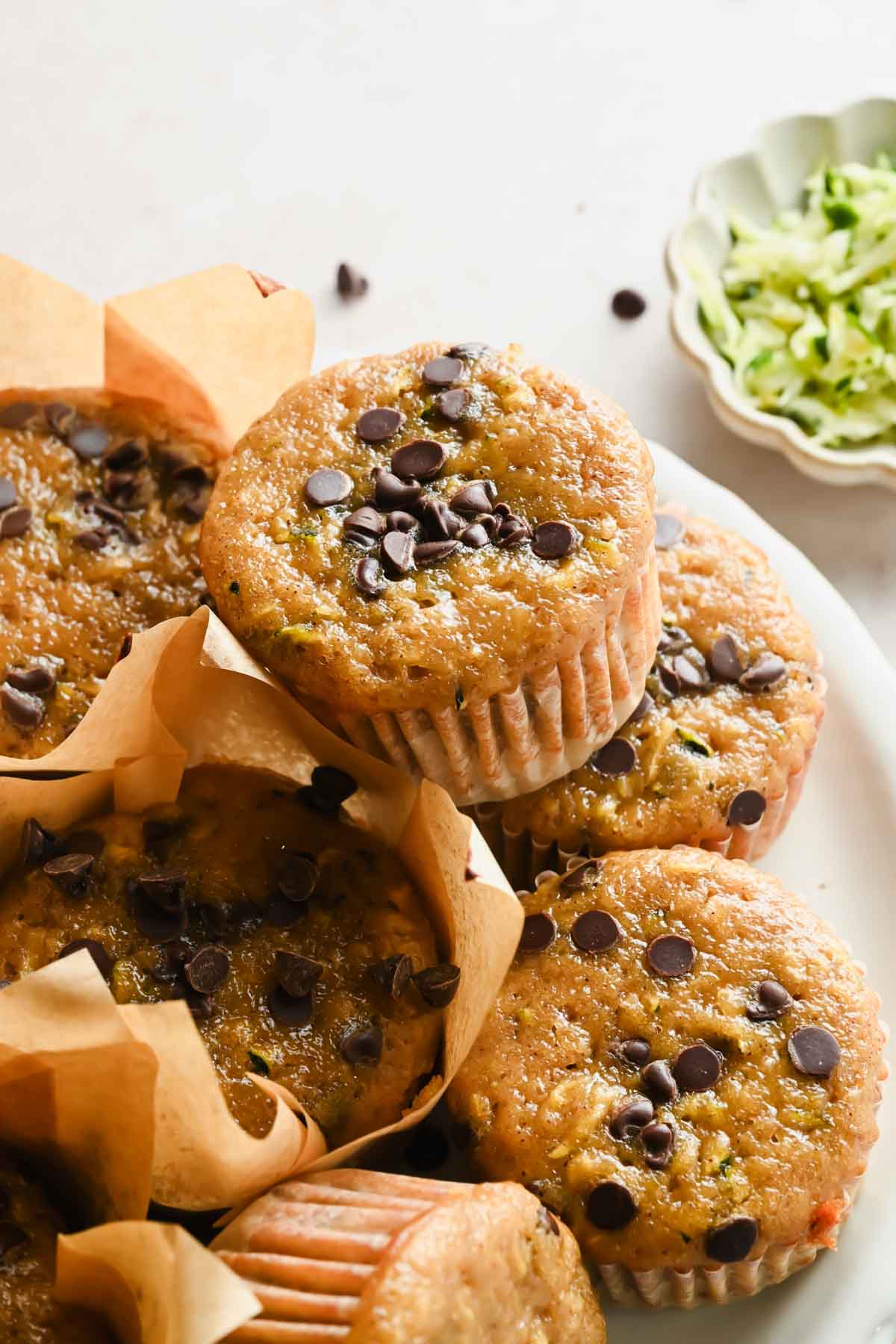 protein zucchini muffins in liners on white plate.