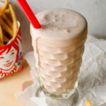healthy wendy's frosty over flowing in a milk shake glass with red straw.