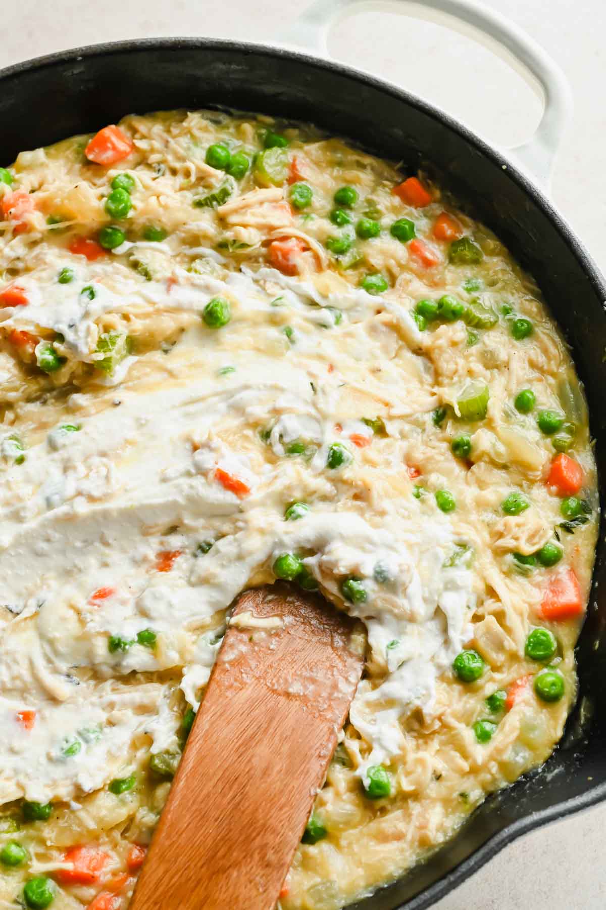 cottage cheese being stirred into chicken pot pie mixture spread in large skillet.