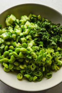 edamame, cucumber, green onion and fresh herbs in large bowl.