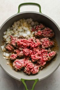 ground beef and diced onions cooking in large skillet.