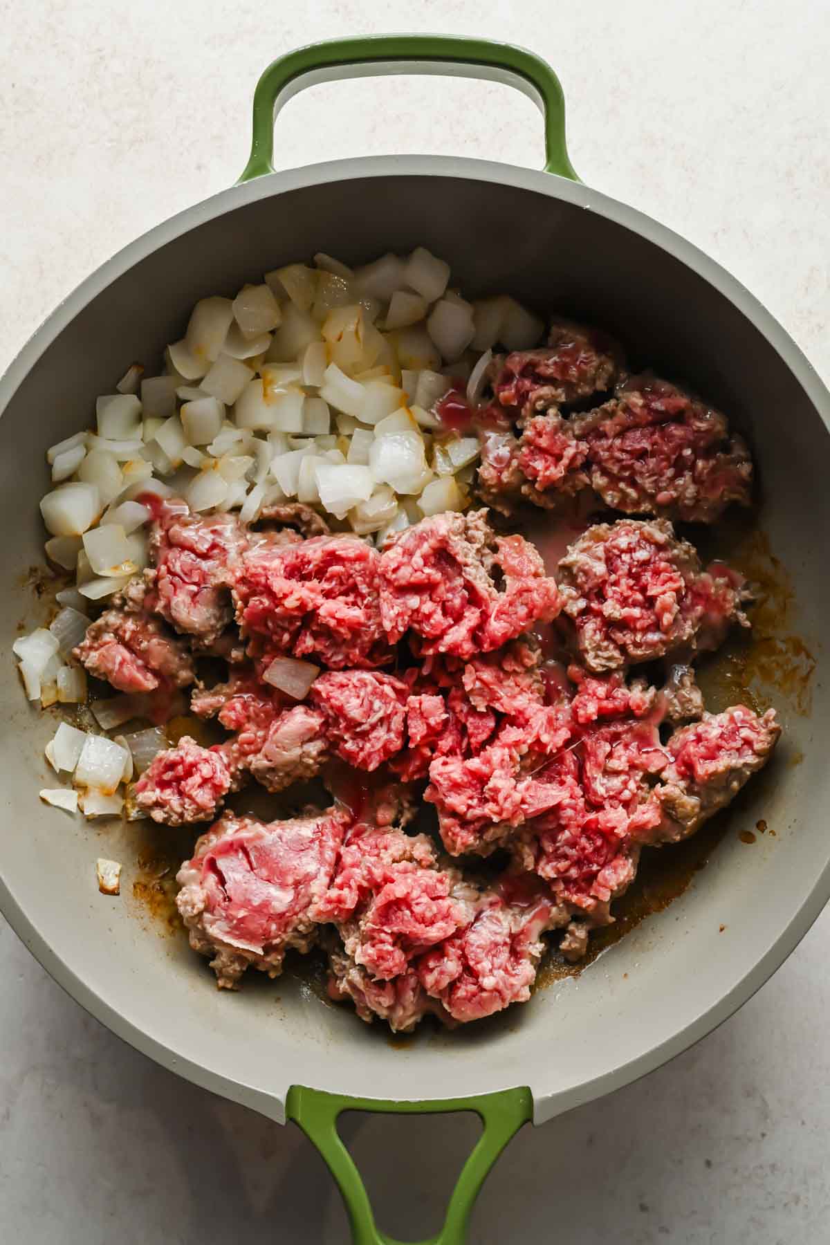 ground beef and diced onions cooking in large skillet.