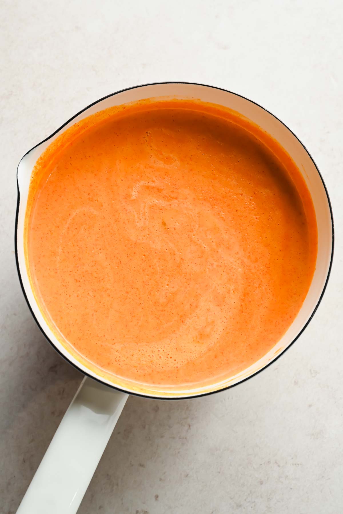 spicy coconut sauce in large white sauce pan.